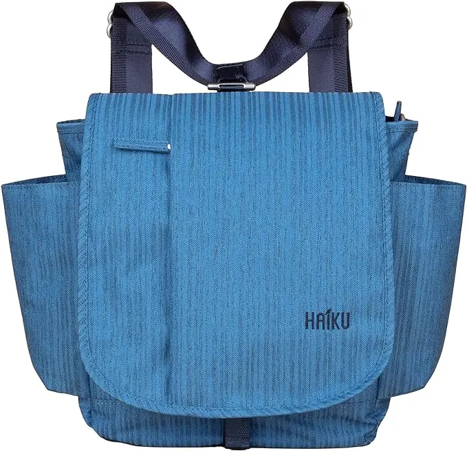 Blue backpack with a rounded flap front, dark shoulder straps, and wide side pockets. The textured fabric has a subtle vertical pattern with the Haiku logo printed near the lower right side.