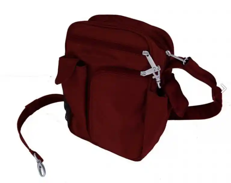 Deep red crossbody travel bag with an adjustable shoulder strap and multiple zippered compartments. The structured bag has a large front pocket and open side pockets with silver zipper hardware.
