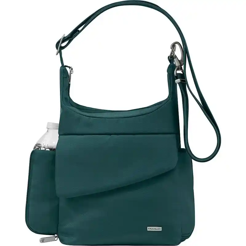 Teal crossbody travel bag with an adjustable shoulder strap and silver clips. It has a large angled front pocket and a side pocket holding a water bottle.